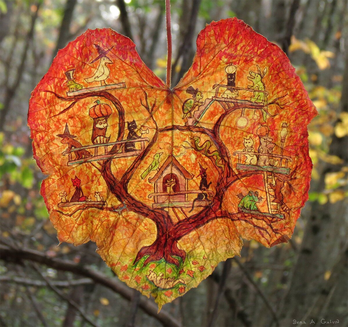 A bustling Halloween treehouse of cats, witches, owls and creatures drawn on a fiery orange heart-shaped grape leaf, against bare forest, by Sera Autumn
