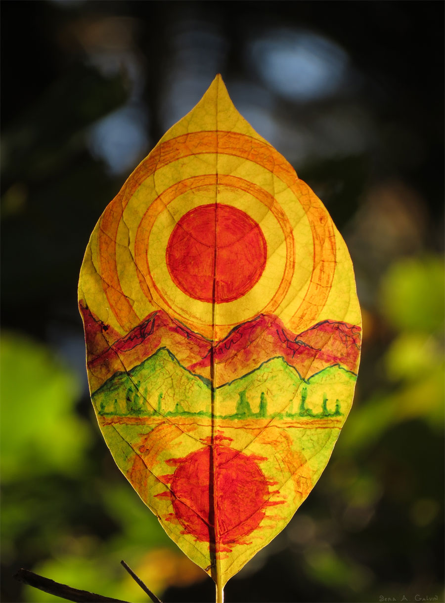 A red sun and its reflection over green and red mountains and water, drawn on a backlit yellow-orange leaf, by Sera Autumn