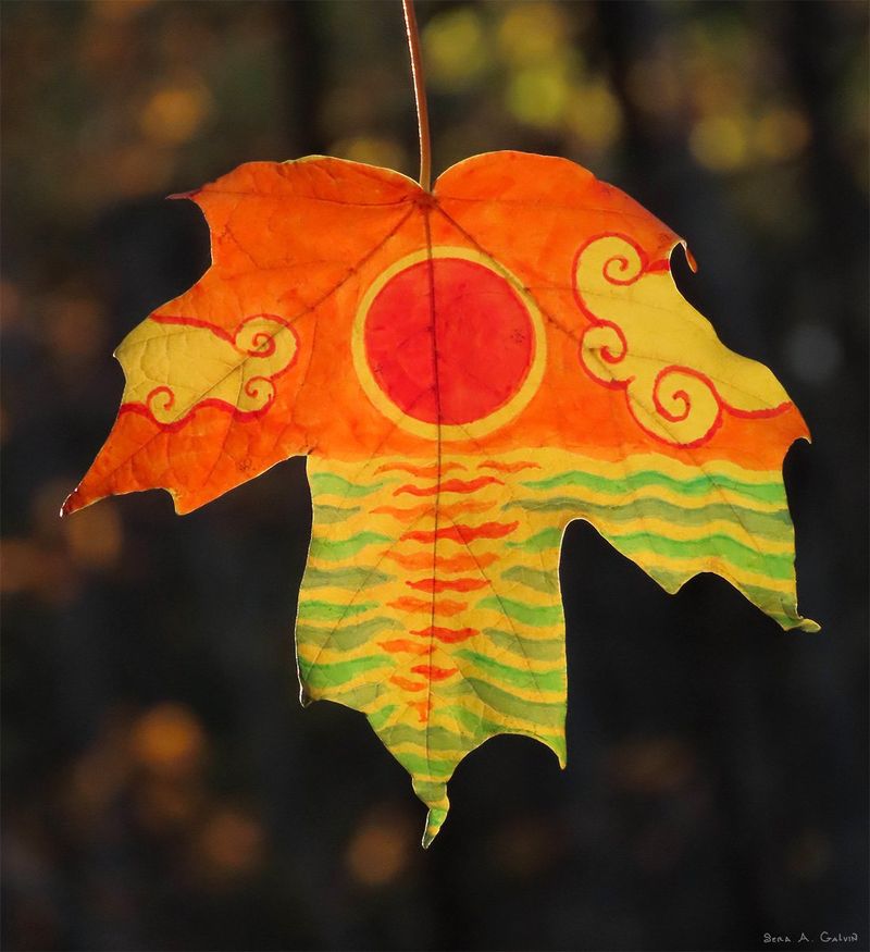 A red setting sun with swirling clouds over rippled water, drawn on a yellow maple leaf against dark bokeh, by Sera Autumn