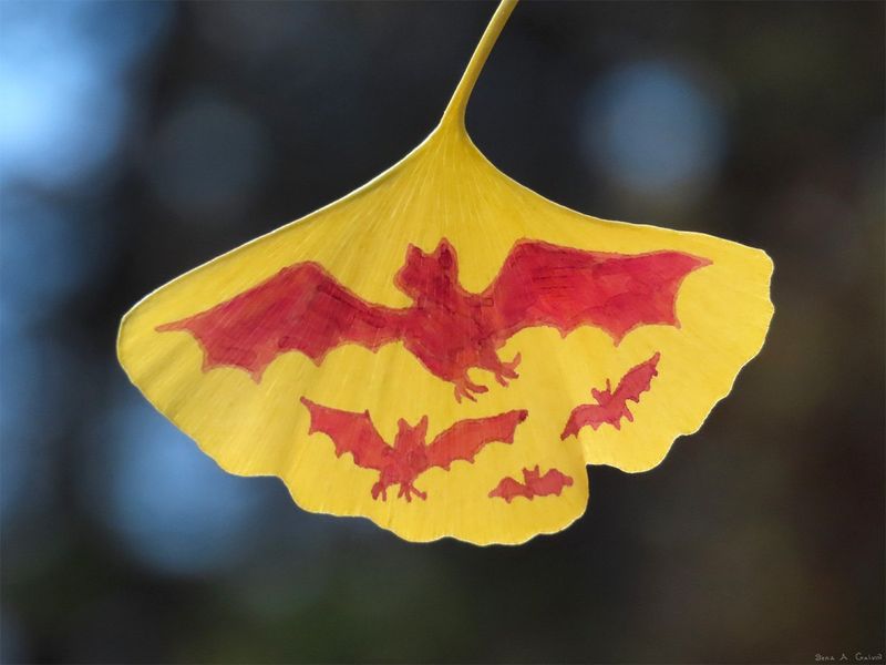 A flock of red bats in flight silhouetted on a bright yellow ginkgo leaf, against blurred blue dusk forest bokeh, by Sera Autumn