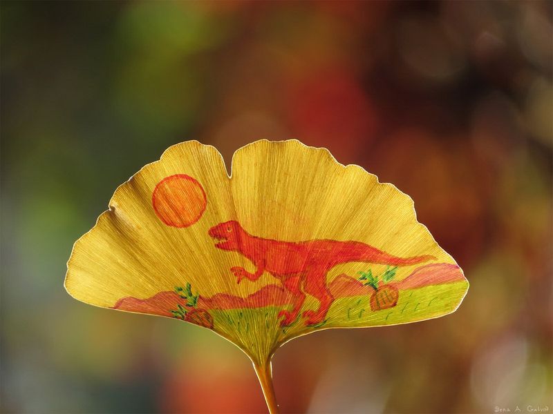 A red T. rex dinosaur beneath an orange sun, drawn on a golden ginkgo leaf, by Sera Autumn