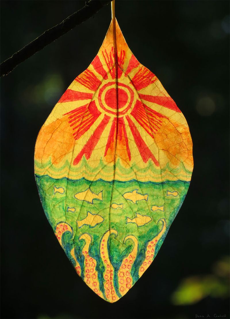 A radiant red-rayed sun rising over a green sea of fish and octopus tentacles, drawn on a backlit yellow leaf, by Sera Autumn