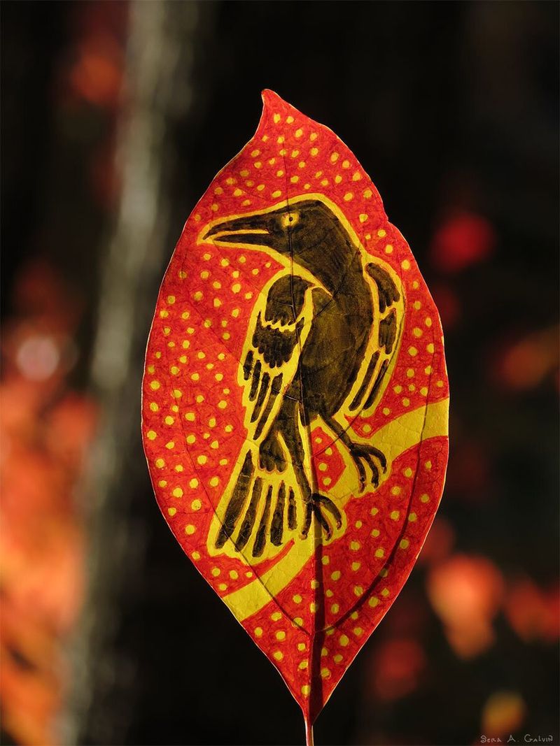 A perched black crow on yellow polka dots, drawn on a glowing red leaf against dark autumn bokeh, by Sera Autumn