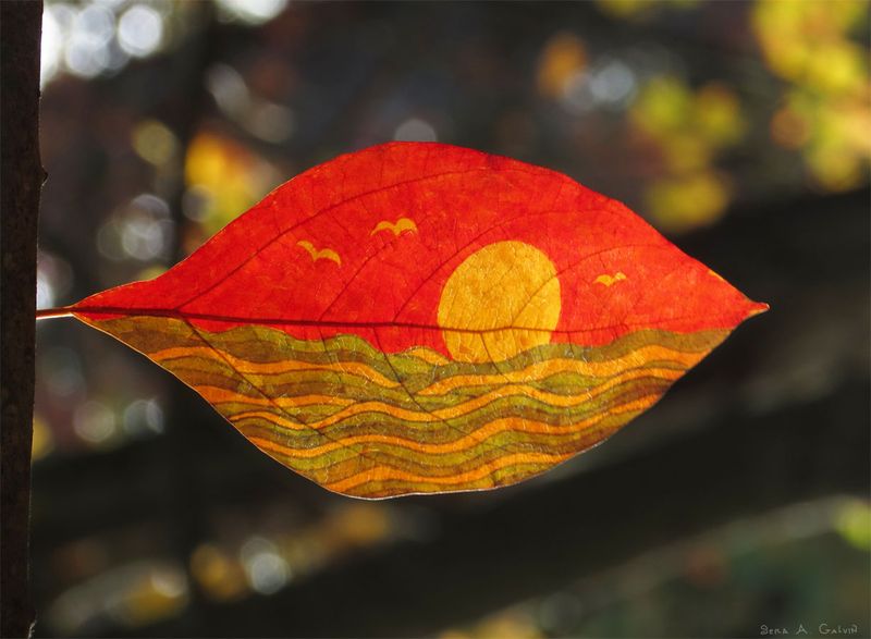 A glowing sunset scene with golden sun, gulls, and wavy sea drawn on a red-and-amber leaf, backlit against dark bokeh, by Sera Autumn